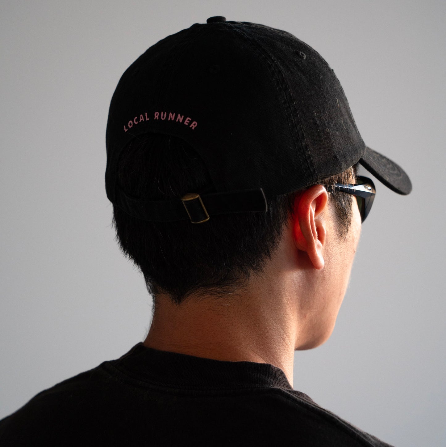 A black cap with 'LOCAL RUNNER' embroidery on the back