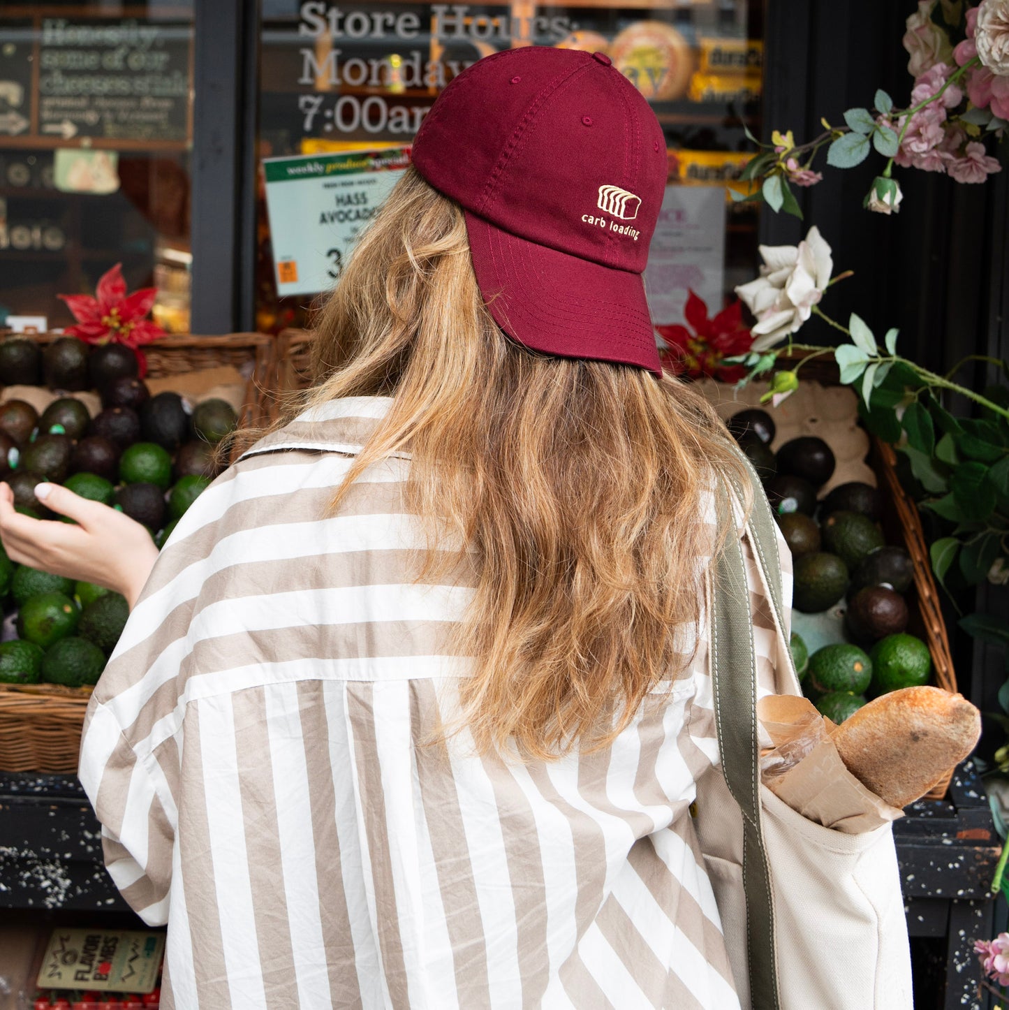 A maroon cap with a carb loading embroidery at an outdoor market.
