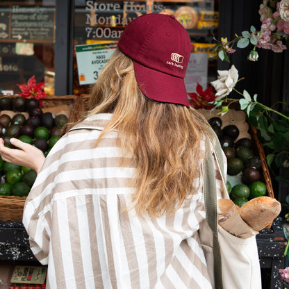 A maroon cap with a carb loading embroidery at an outdoor market.