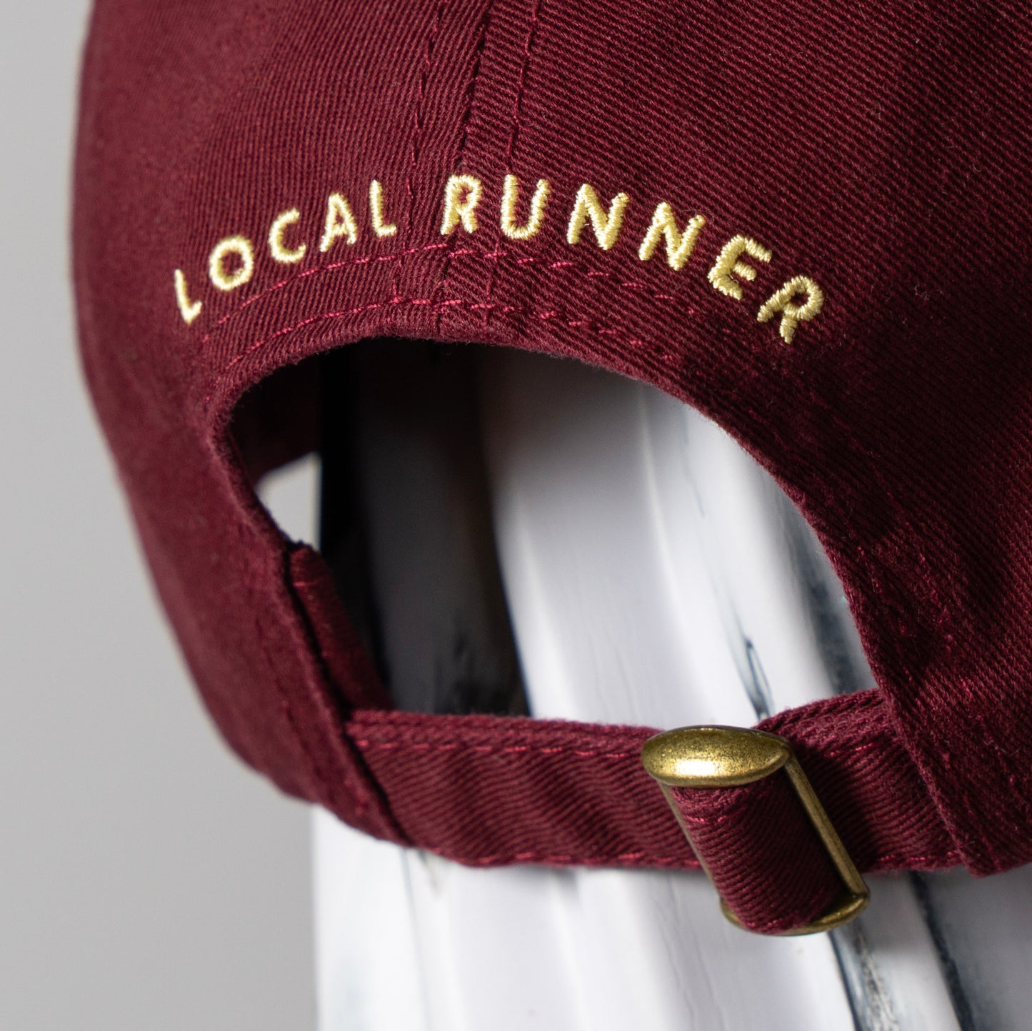 A maroon cap with 'LOCAL RUNNER' embroidery