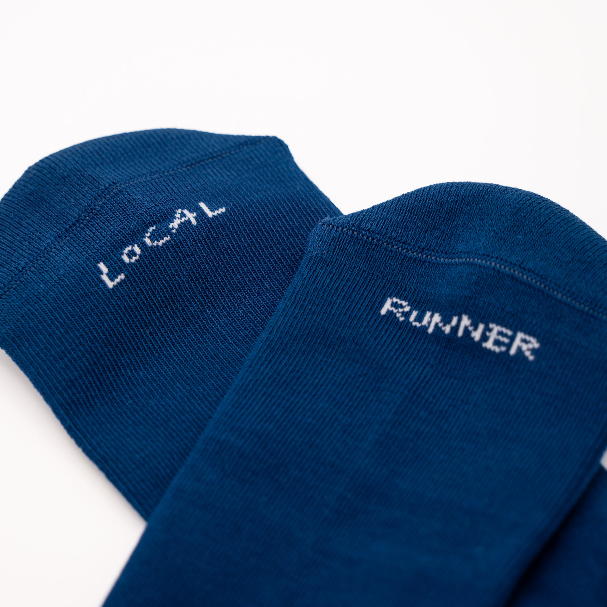 Two navy blue crew socks on a white background, one with 'LOCAL' and the other with 'RUNNER' embroidered in white.