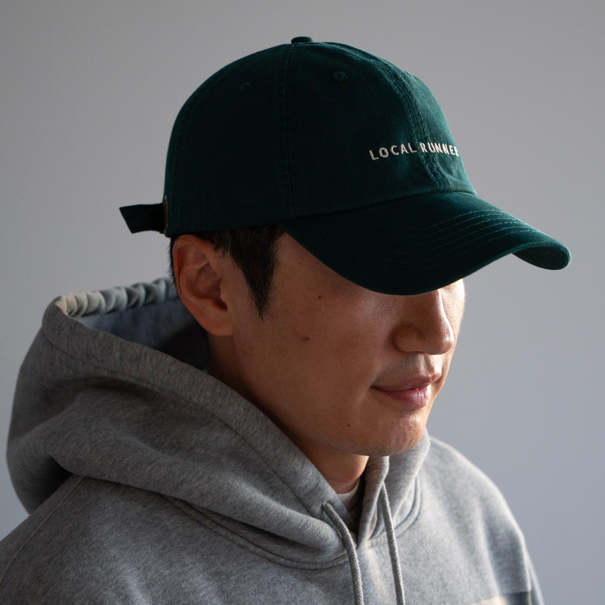 A dark green cap with 'LOCAL RUNNER' embroidery