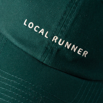 A dark green cap with 'LOCAL RUNNER' embroidered on it