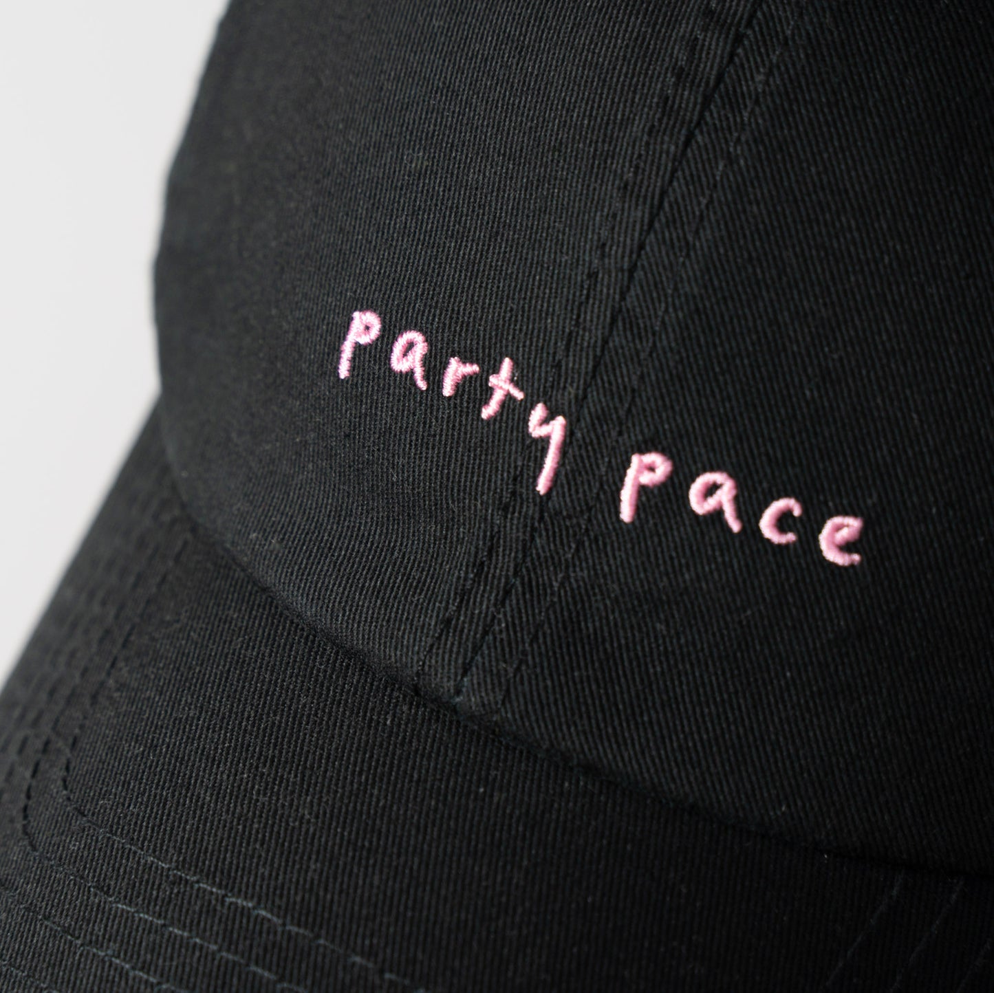 A Black cap with 'Party Pace' embroidered in pink