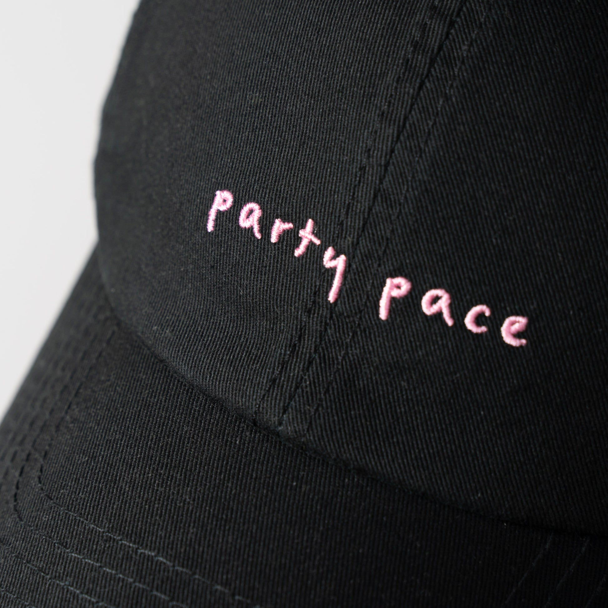A Black cap with 'Party Pace' embroidered in pink