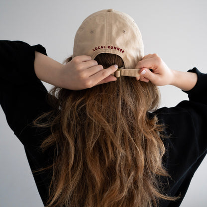 A beige cap with 'LOCAL RUNNER' embroidery 